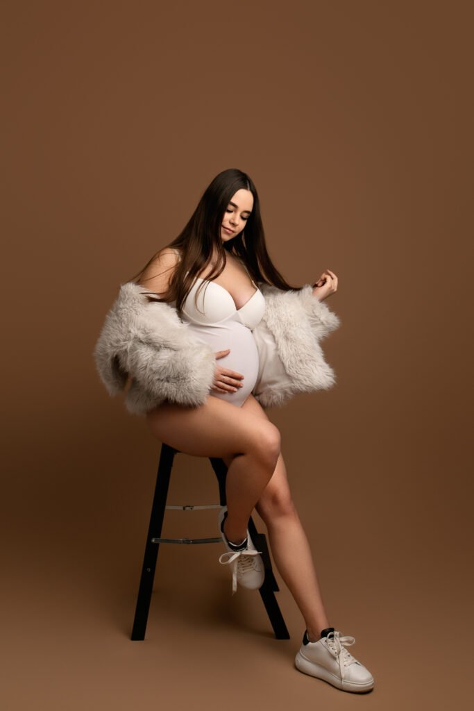 Profil brzucha ciążowego na neutralnym beżowym tle - minimalistyczne ujęcie